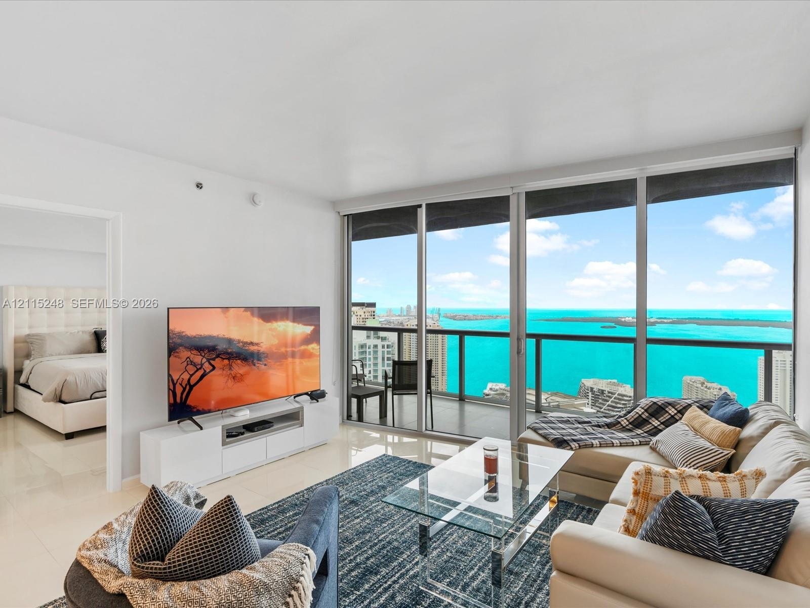 Floor-to-ceiling glass sliding doors, private balcony with metal railing, and light-toned tile flooring