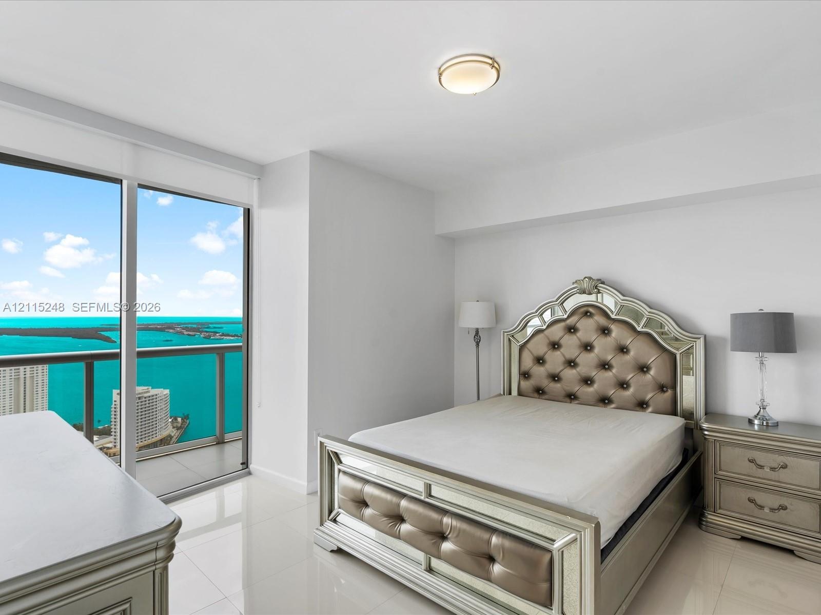 Floor-to-ceiling windows featuring expansive coastal and urban water panoramas, complemented by polished tile flooring and a flush-mount overhead ligh