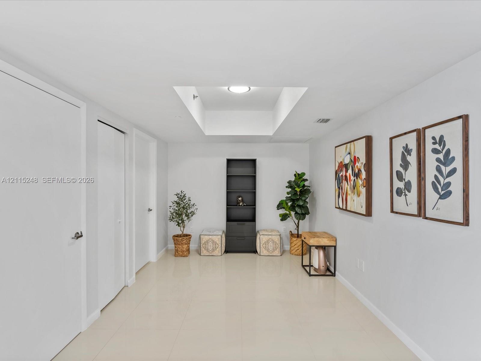 Interior space featuring large-format tile flooring, recessed ceiling lighting, a dedicated rectangular skylight, and multiple interior swing-style do