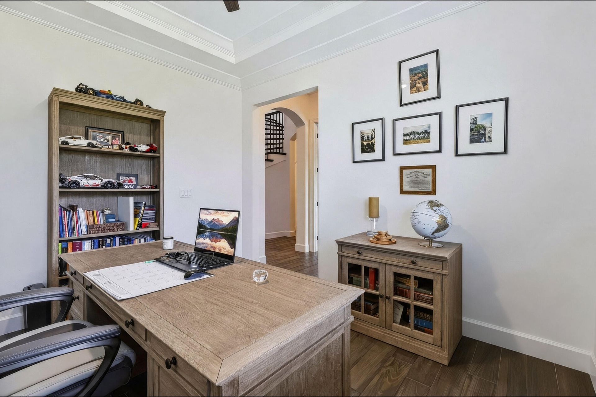 Room featuring tray ceilings, wood-finish flooring, and an arched doorway