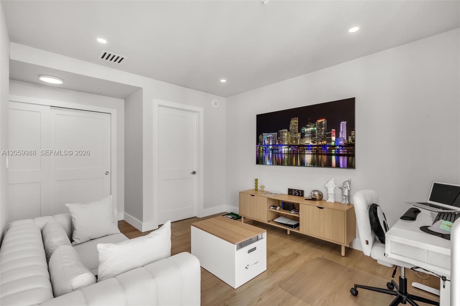 Neutral-toned room featuring wood-finish flooring, recessed lighting, and a double-door closet