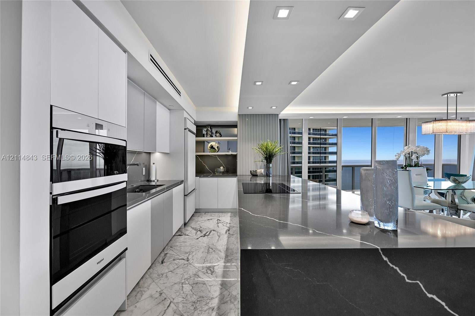 Kitchen featuring high-gloss cabinetry, stone-finish countertops, integrated double wall ovens, recessed ceiling lighting, and floor-to-ceiling window