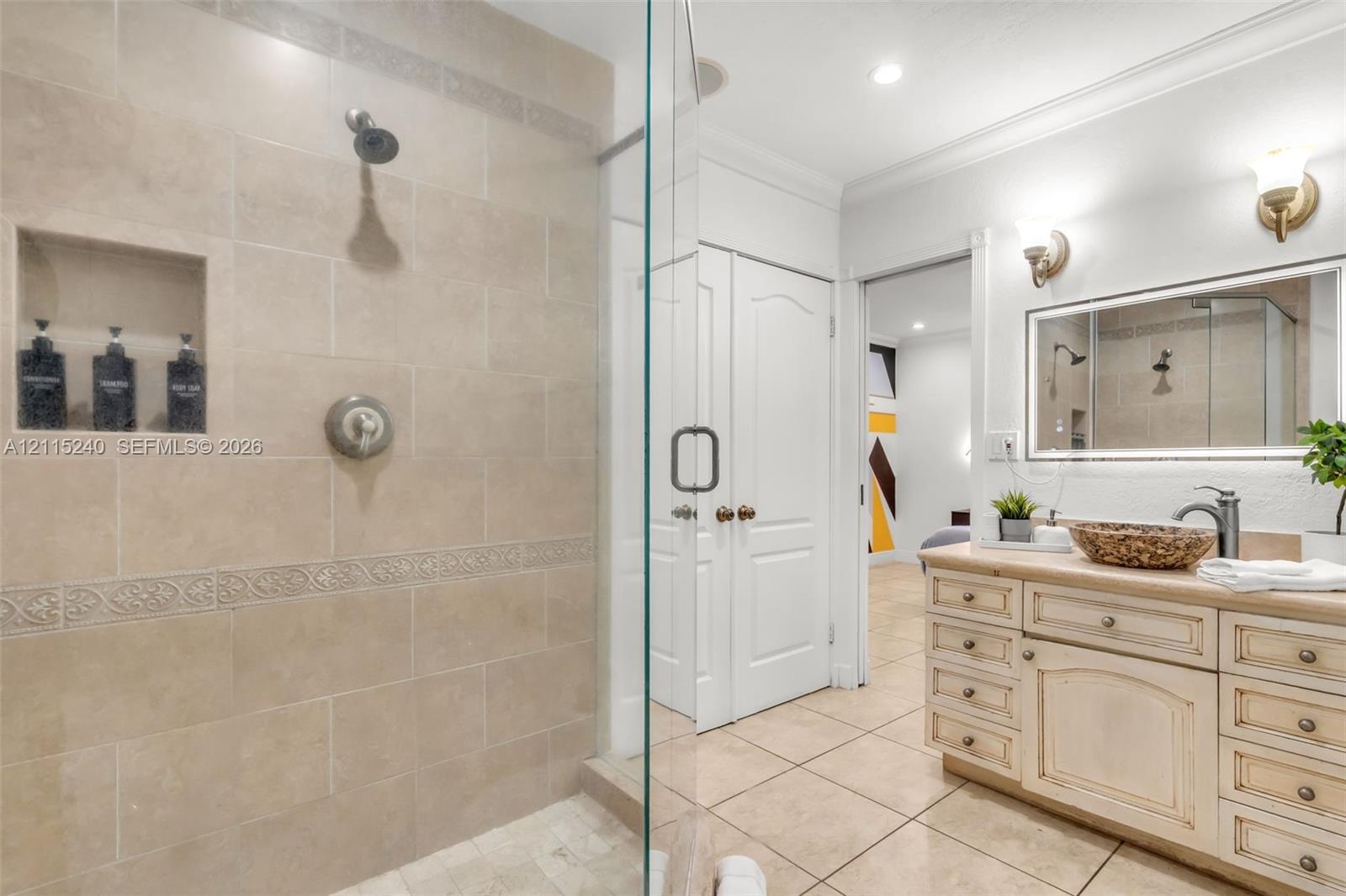 Walk-in shower featuring floor-to-ceiling tile, a built-in recessed storage niche, and a glass enclosure, paired with a custom vanity cabinet and fram