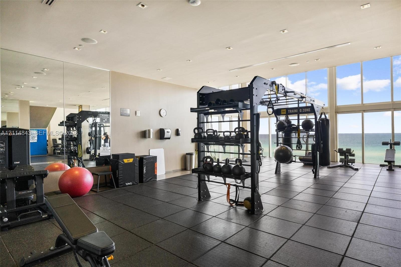 Fitness center featuring floor-to-ceiling windows, full-wall mirrors, and durable rubber flooring