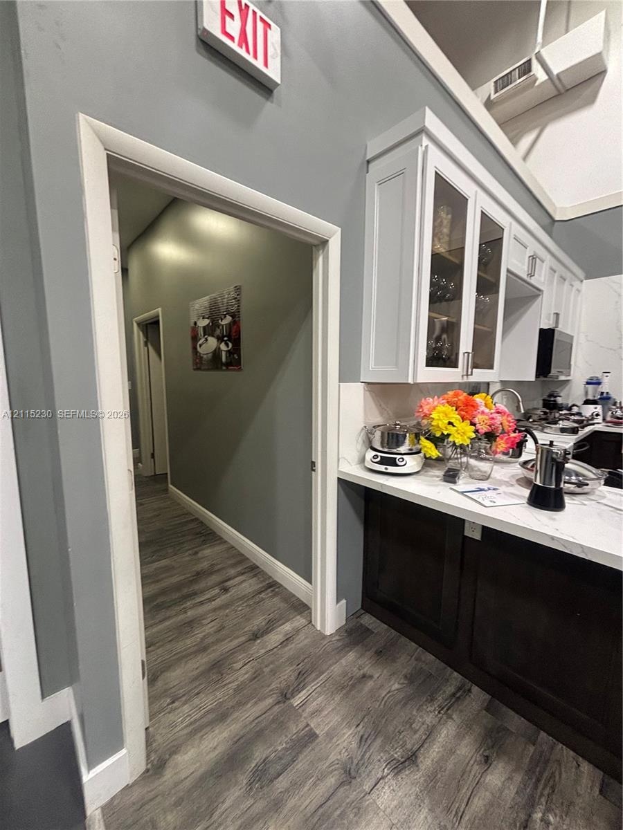 Two-tone cabinetry featuring white upper glass-front cupboards and dark lower base cabinets, complemented by white stone-surface countertops and wood-
