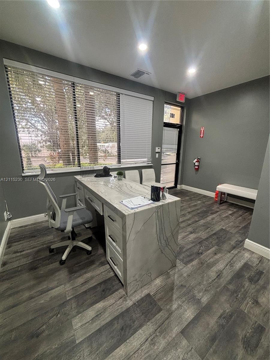 Room featuring wood-finish flooring, recessed lighting, and a large multi-pane window with integrated blinds