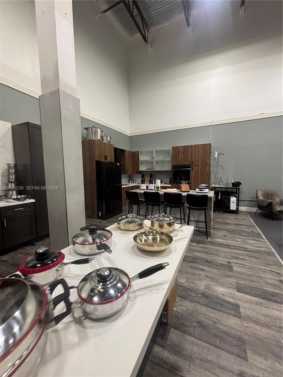 Kitchen featuring double-height ceilings, wood-finish cabinetry, a central island with quartz surfacing, and wood-finish flooring