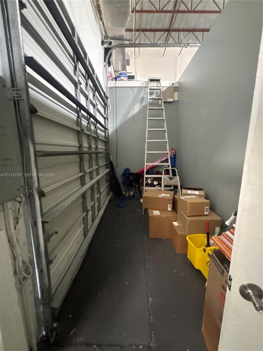 Storage area featuring exposed structural ceiling, metal roll-up door, and high-clearance vertical wall space