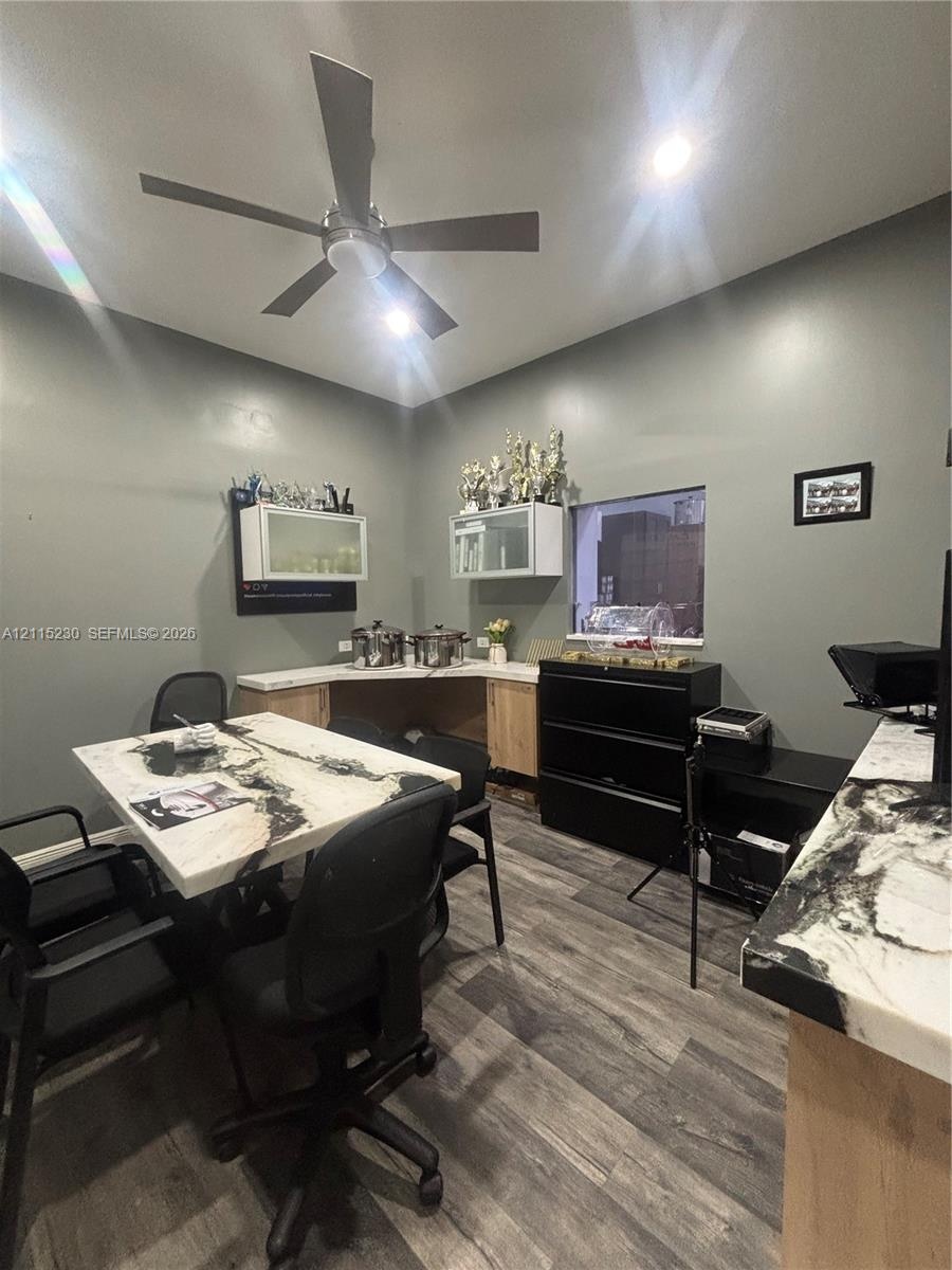 Wood-finish flooring, custom built-in cabinetry with stone-finish countertops, and a modern ceiling fan