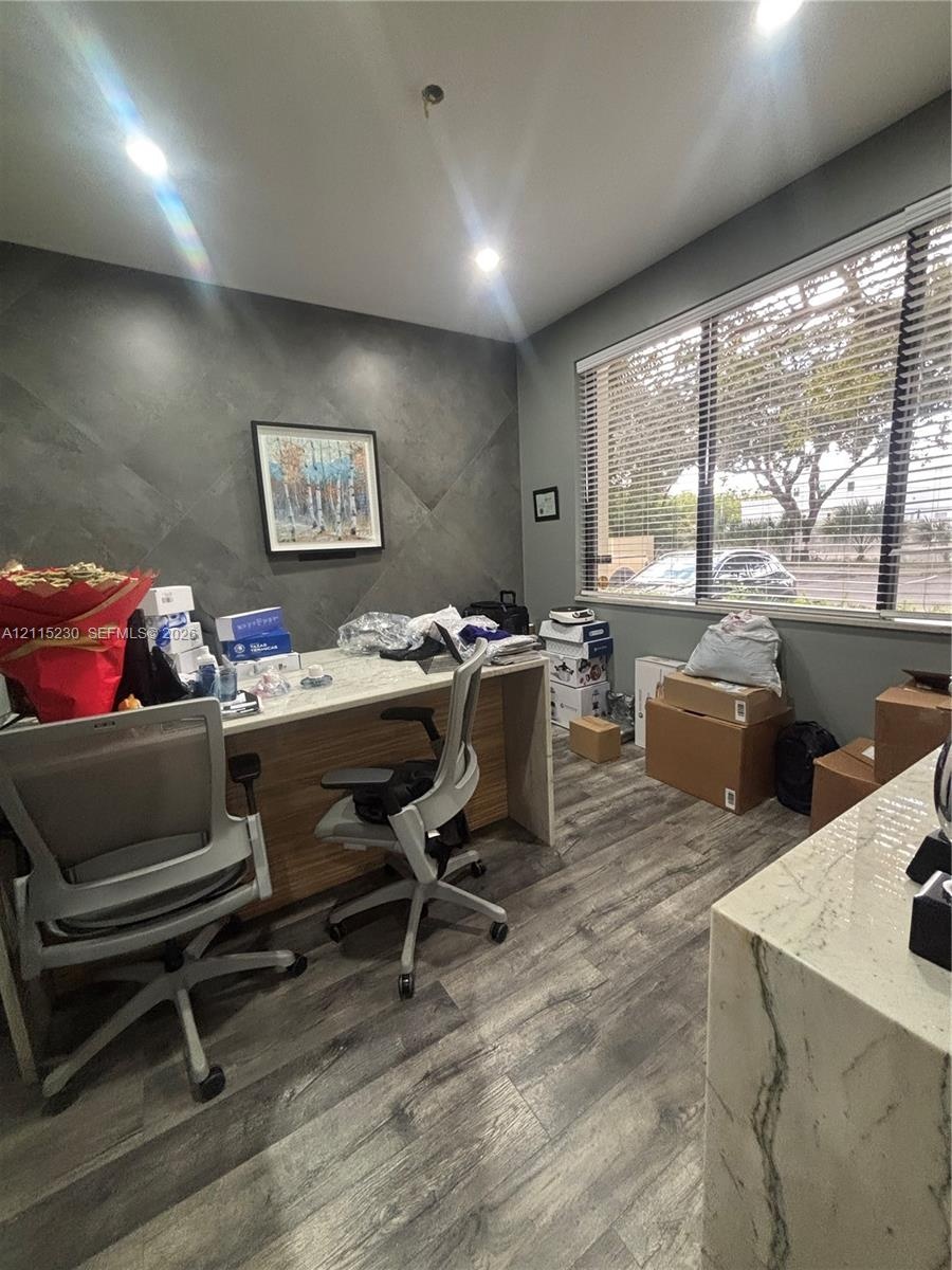 Room featuring wood-finish flooring, recessed lighting, and a textured geometric accent wall