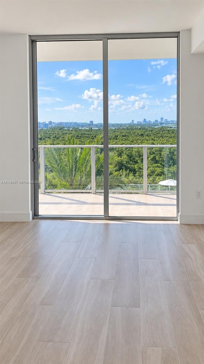 Full-height sliding glass doors with aluminum framing, wood-finish flooring, and a private balcony featuring a glass railing