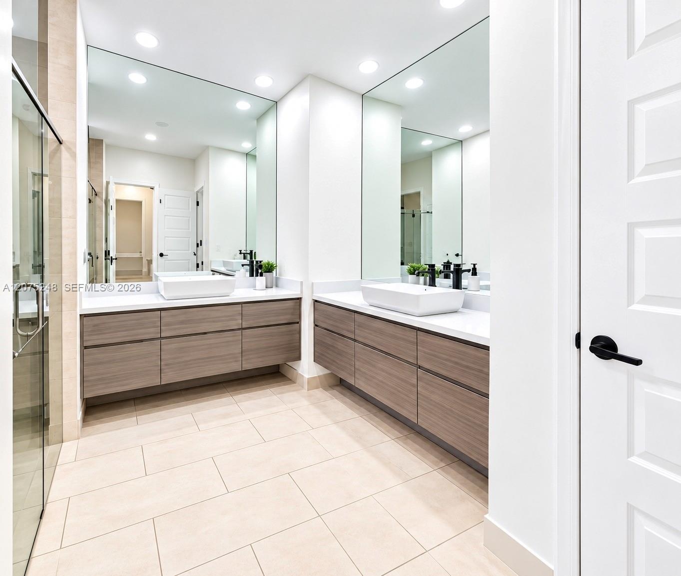 Dual floating vanities with wood-finish MASTERs cabinetry, rectangular vessel sinks, expansive wall-to-wall mirrors, and matte black fixtures, complem