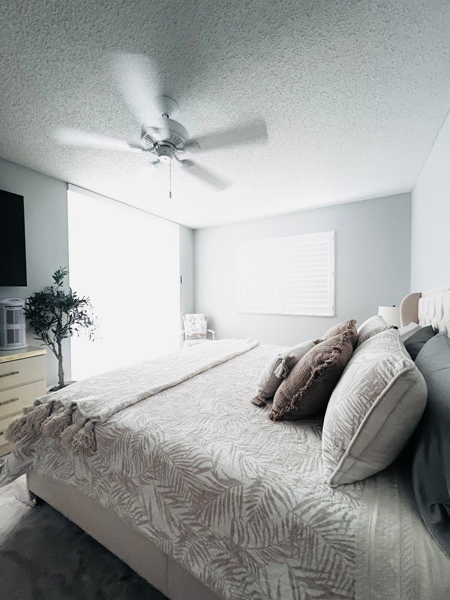 Spacious interior room featuring a ceiling fan, window with horizontal blinds, light-colored walls, and textured ceiling