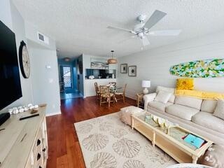 Open-concept living space featuring wood-finish flooring, a ceiling fan with integrated lighting, and a dining area with a built-in banquette