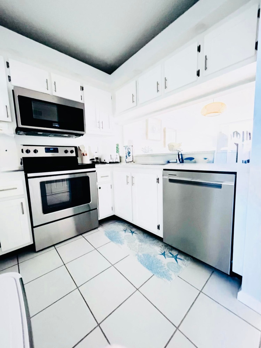 Kitchen featuring white cabinetry with dark hardware, a stainless steel range with an over-the-range microwave, a stainless steel dishwasher, and whit