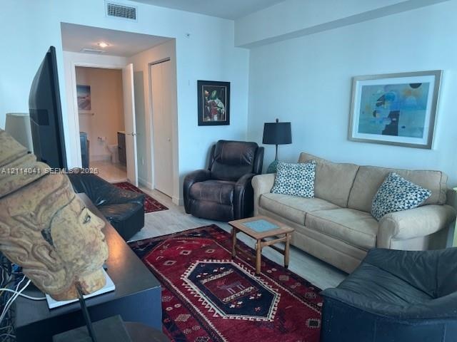 Living area featuring wood-finish flooring, high ceilings, and recessed lighting