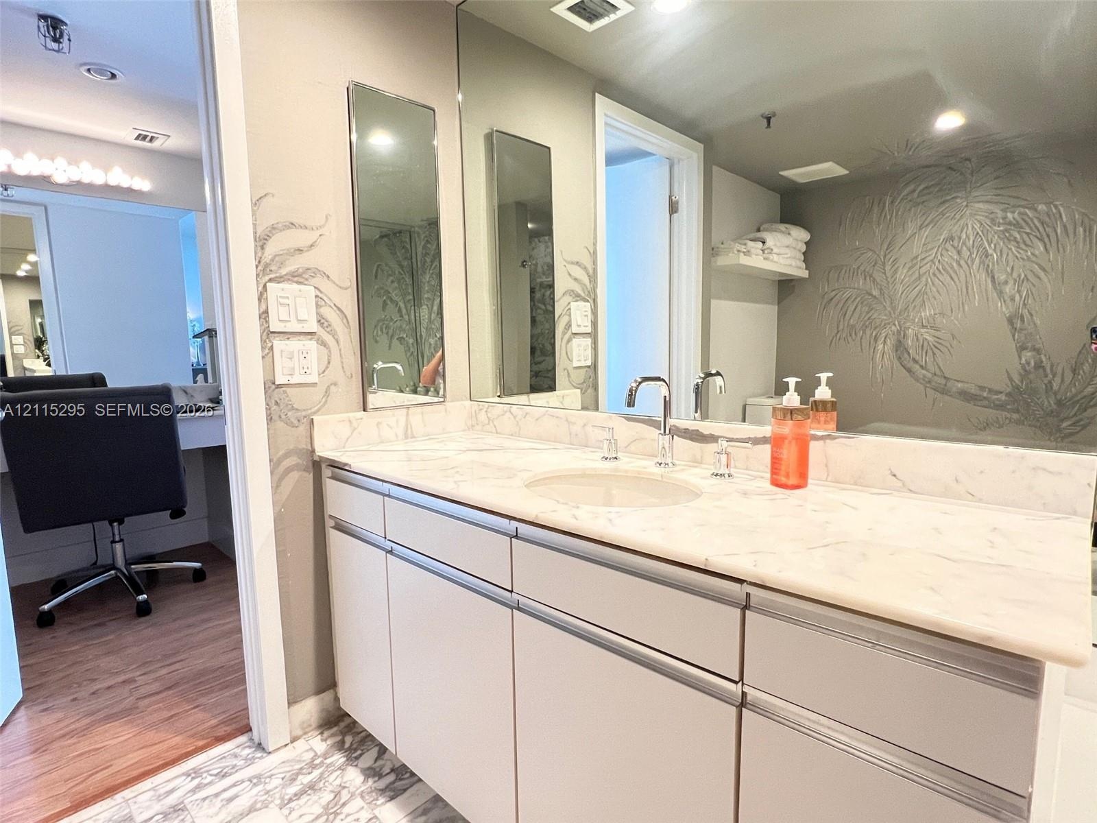 Bathroom vanity featuring a stone-top counter, dual-handle metal faucets, integrated sinks, and neutral cabinetry