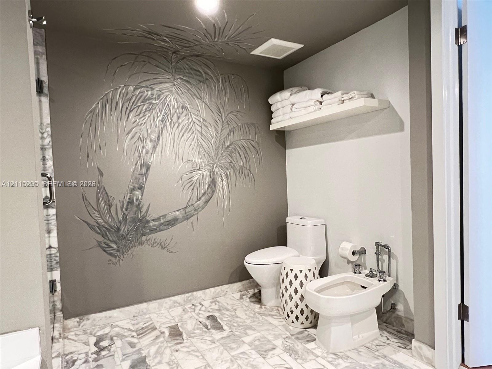 Bathroom featuring stone tile flooring, a wall-mounted display shelf, and a custom mural