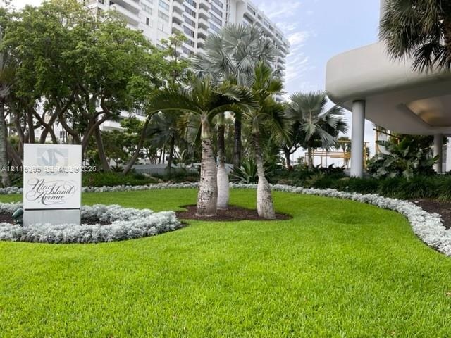 Landscaped grounds featuring a manicured lawn, established palm trees, mature canopy trees, and low-lying groundcover plantings
