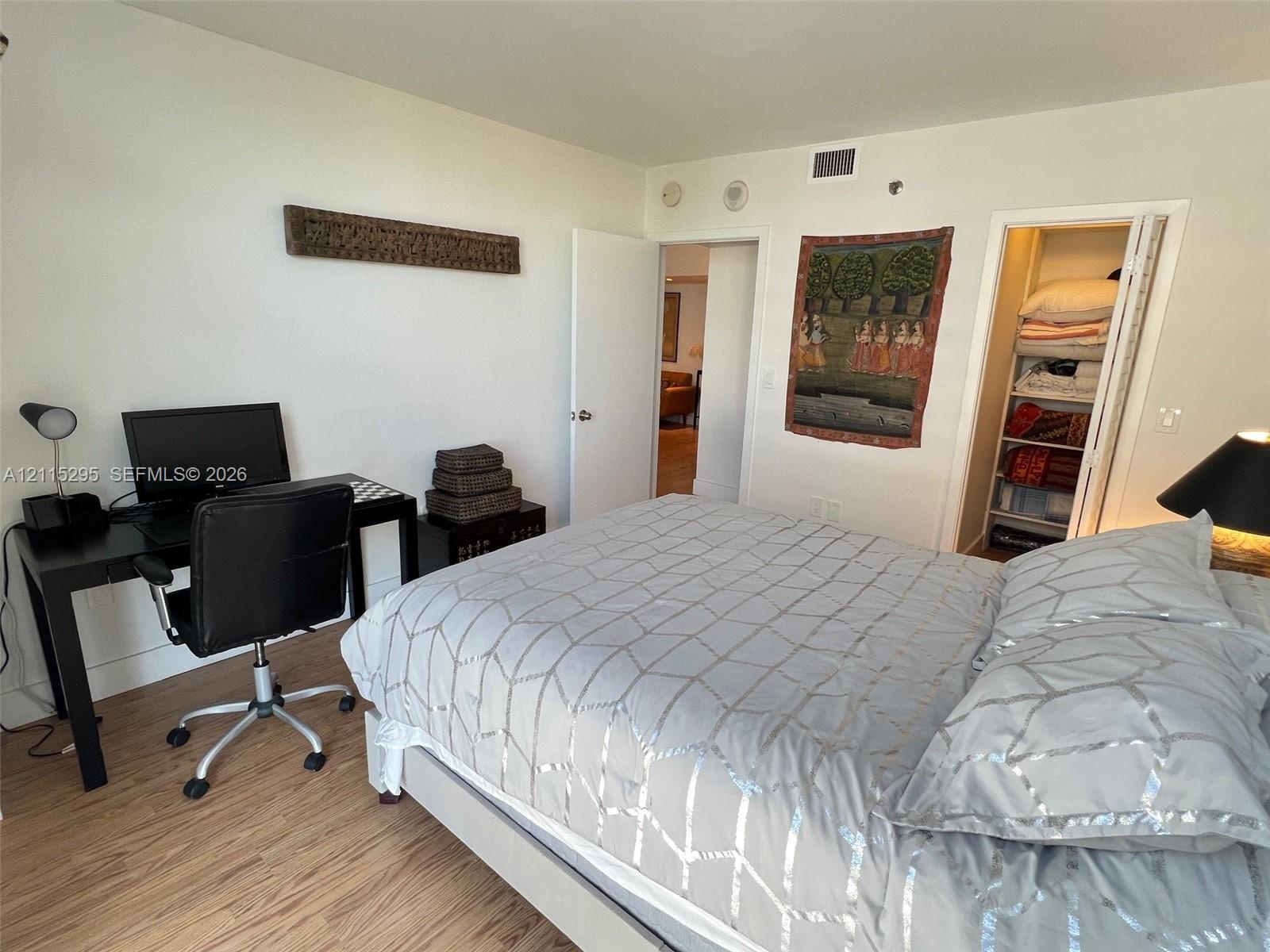 Neutral-toned interior featuring wood-finish flooring, a bi-fold door closet with built-in shelving, and a solid-core interior door