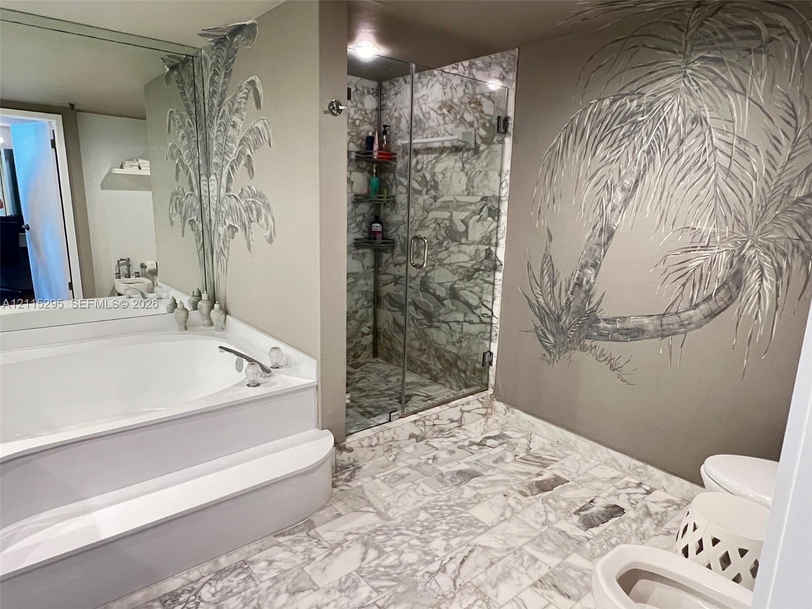 Bathroom featuring a soaking tub with a tiered surround, a glass-enclosed shower with stone-tile surround, and stone-tile flooring