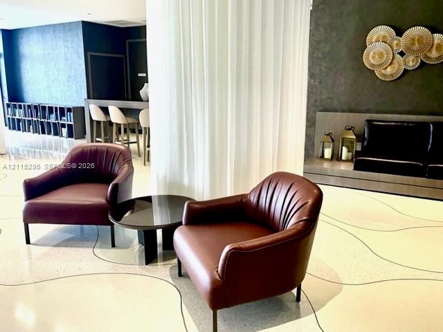 Polished terrazzo flooring featuring inlaid dark grout lines, textured charcoal wall treatment, built-in recessed platform seating, and floor-to-ceili