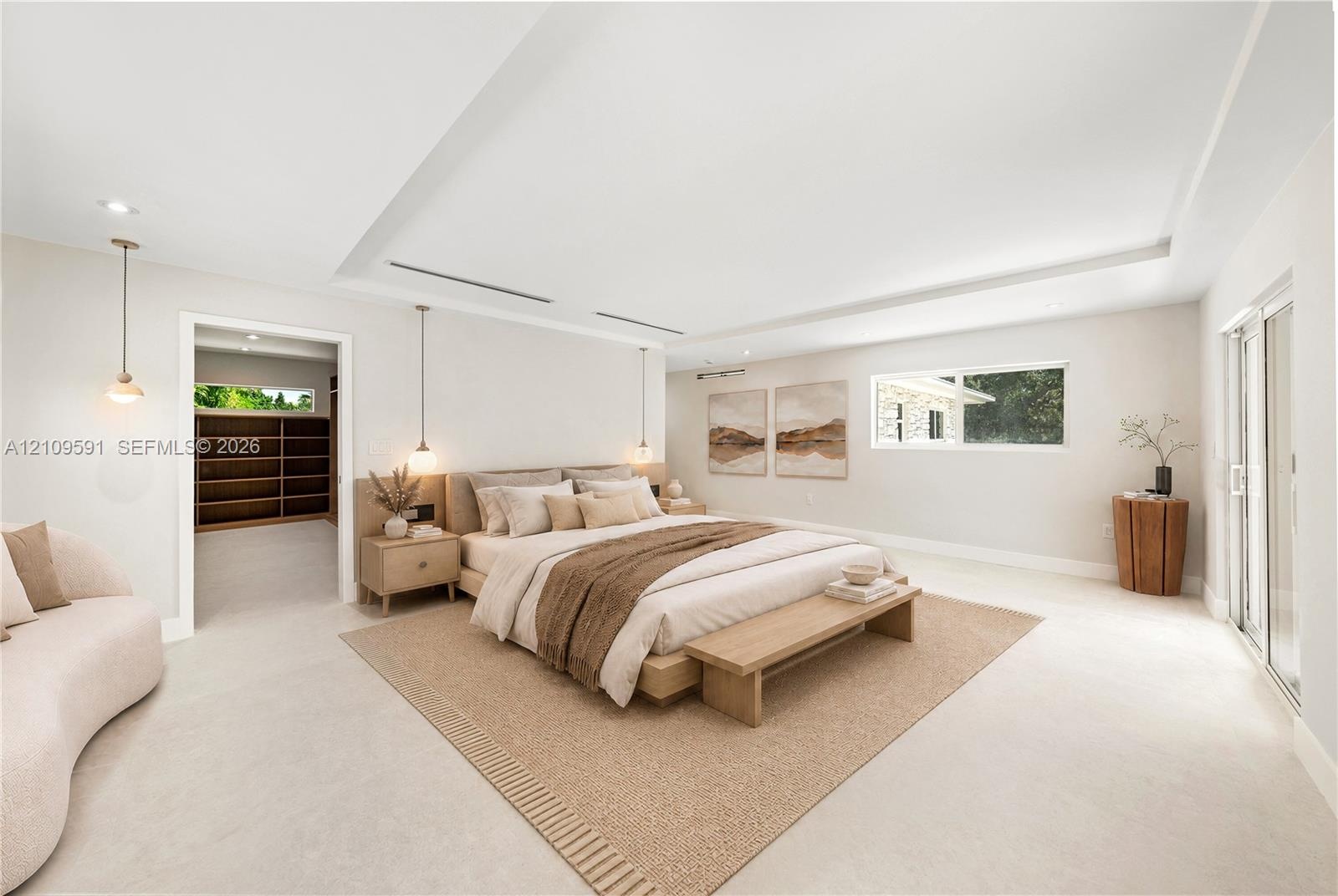 Virtually Staged: Spacious room with recessed tray ceiling, neutral stone-finish flooring, built-in shelving, pendant lighting, and sliding glass door