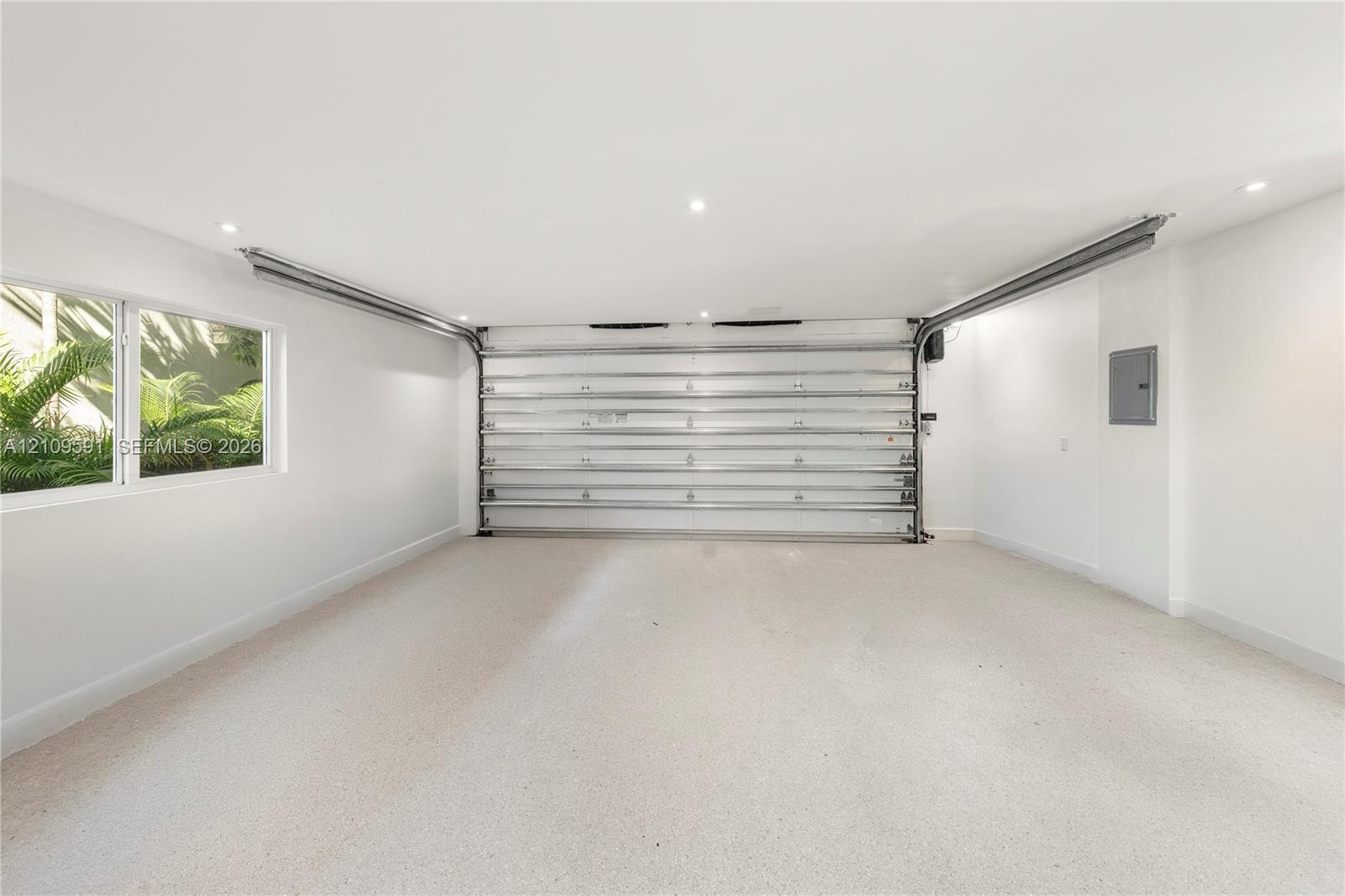 Finished interior garage space featuring recessed lighting, a smooth-finish floor, a multi-panel overhead door, and a side window providing natural li