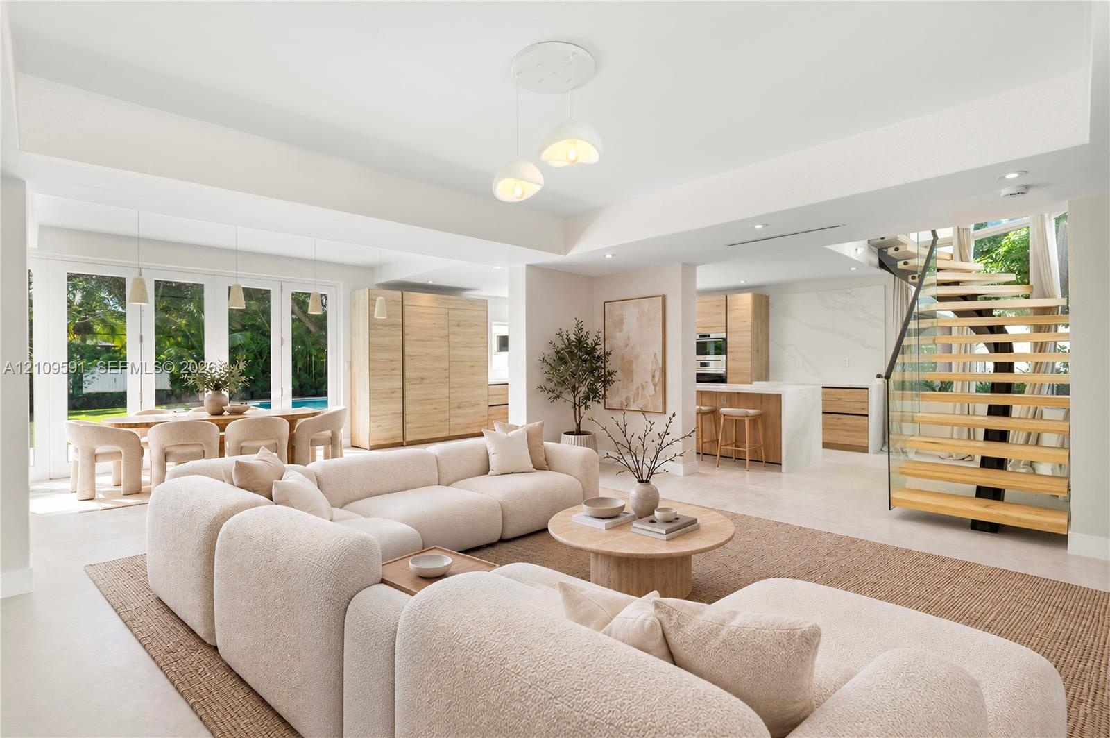 Virtually Staged: Open-concept living space featuring high tray ceilings, wood-finish cabinetry, a modern staircase with glass railings and wood tread