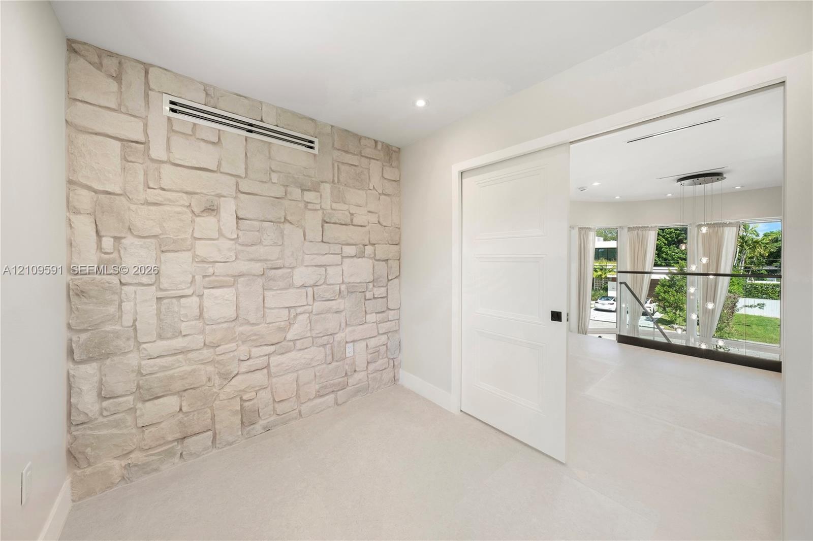 Textured stone feature wall with recessed lighting and three-panel solid core sliding door