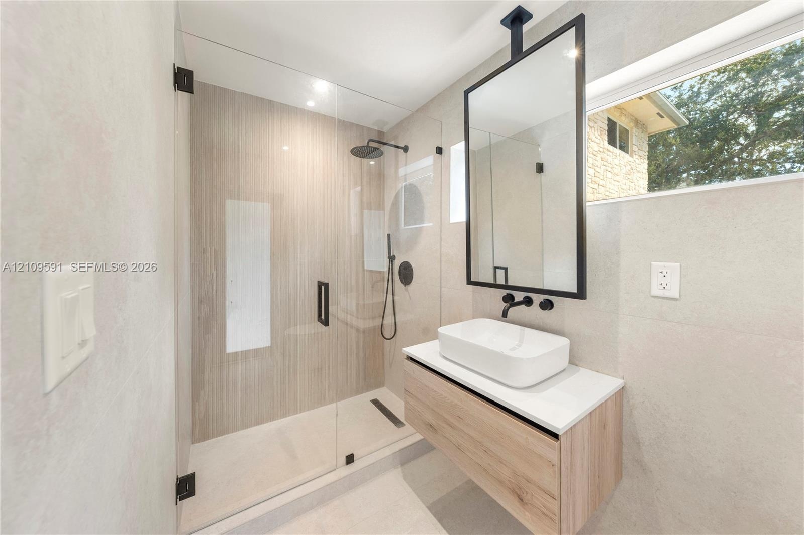 Cabana Bath Floating vanity with rectangular vessel sink and countertop, ceiling-mounted mirror with black frame, walk-in shower with frameless glass 