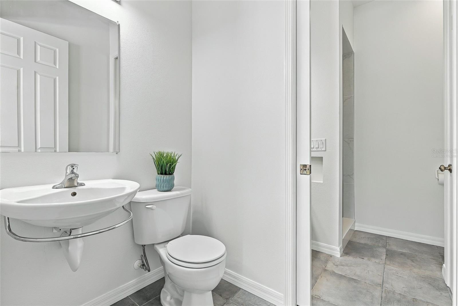 Dually-accessed full bathroom with a half bath easily accessible to the pool. Virtually staged.