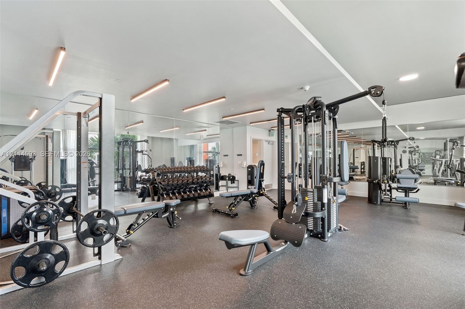 Fitness center featuring mirrored walls, resilient flooring, and integrated linear lighting