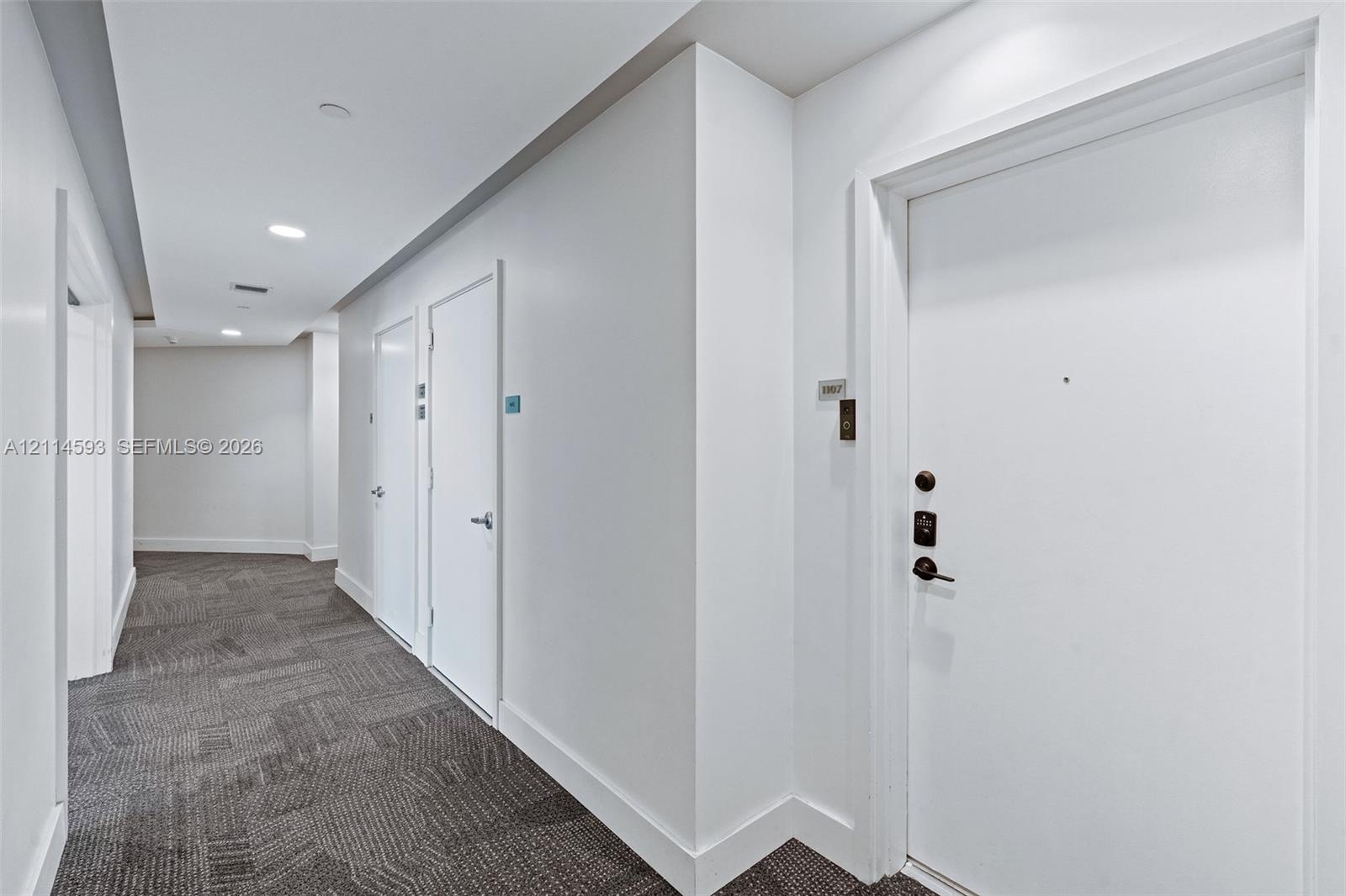 Hallway featuring neutral-toned carpeting, recessed ceiling lighting, and solid-core interior doors with metallic lever hardware
