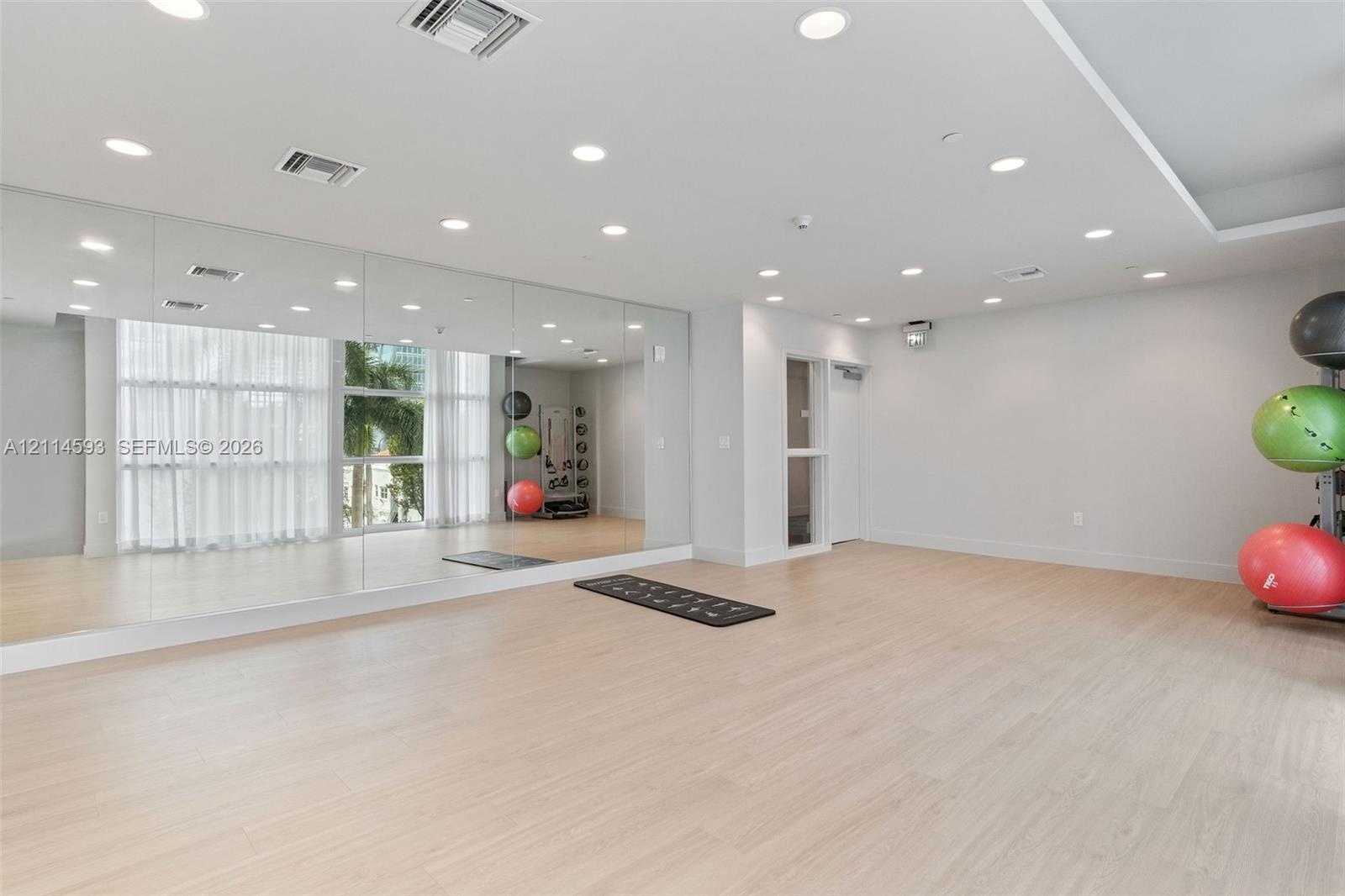 Large wall-mounted mirror, light-toned wood-finish flooring, and recessed ceiling lighting