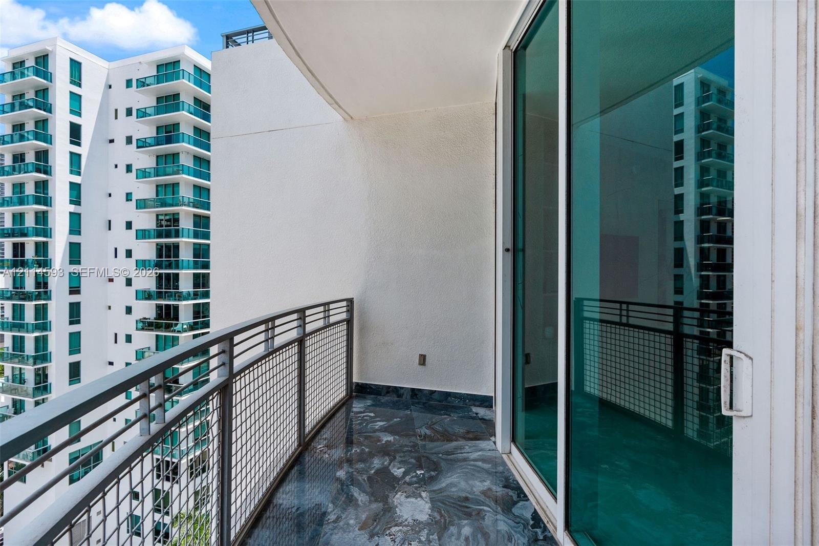 Private balcony featuring polished stone flooring, metal mesh railing, and floor-to-ceiling sliding glass doors