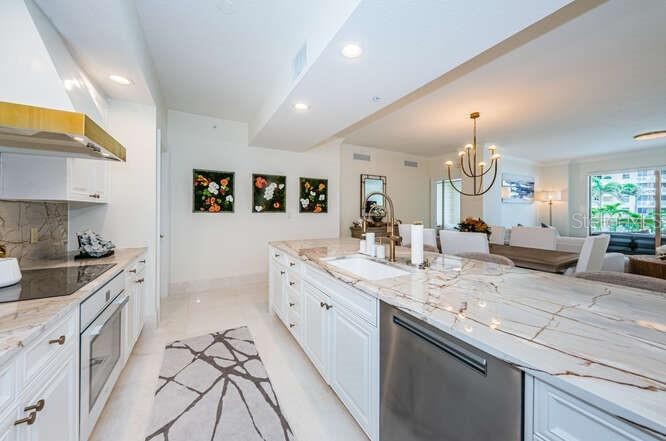 Custom Cucina with a Grand Peninsula, Quartzite Counter & Backsplash Accessorized Stainless Appliances.