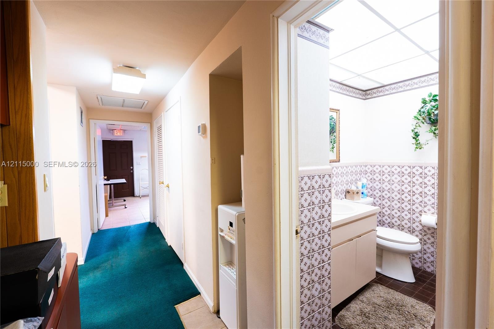 Bathroom featuring patterned wall tiling, a gold-toned faucet, a built-in vanity, a wall-mounted mirrored medicine cabinet, and a drop-in sink