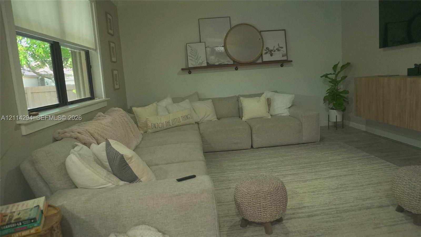 Living area featuring wood-finish flooring, a wall-mounted floating storage cabinet, and a built-in wall shelf