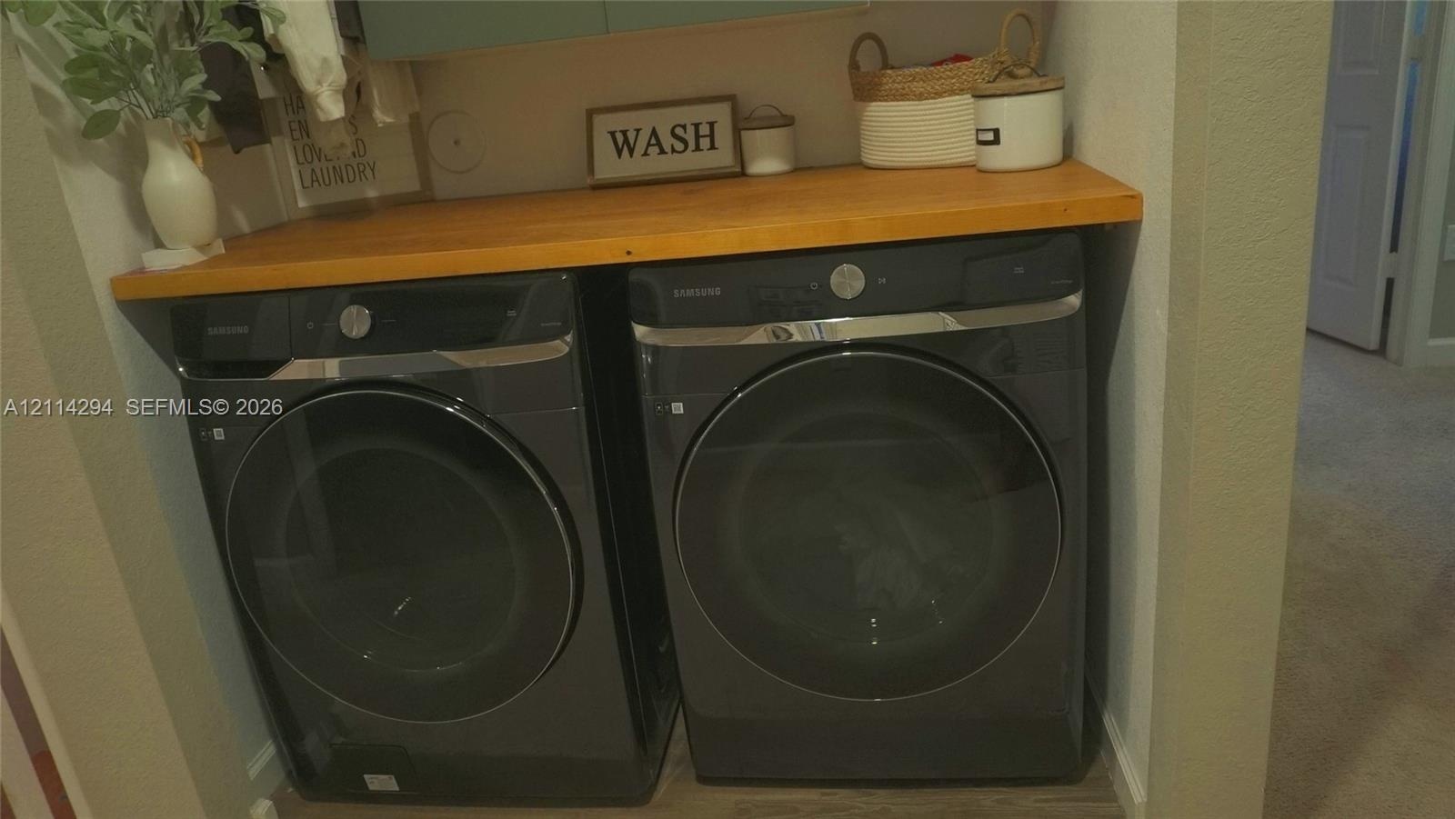 Built-in wooden countertop, wall-mounted cabinetry, and side-by-side front-loading appliances