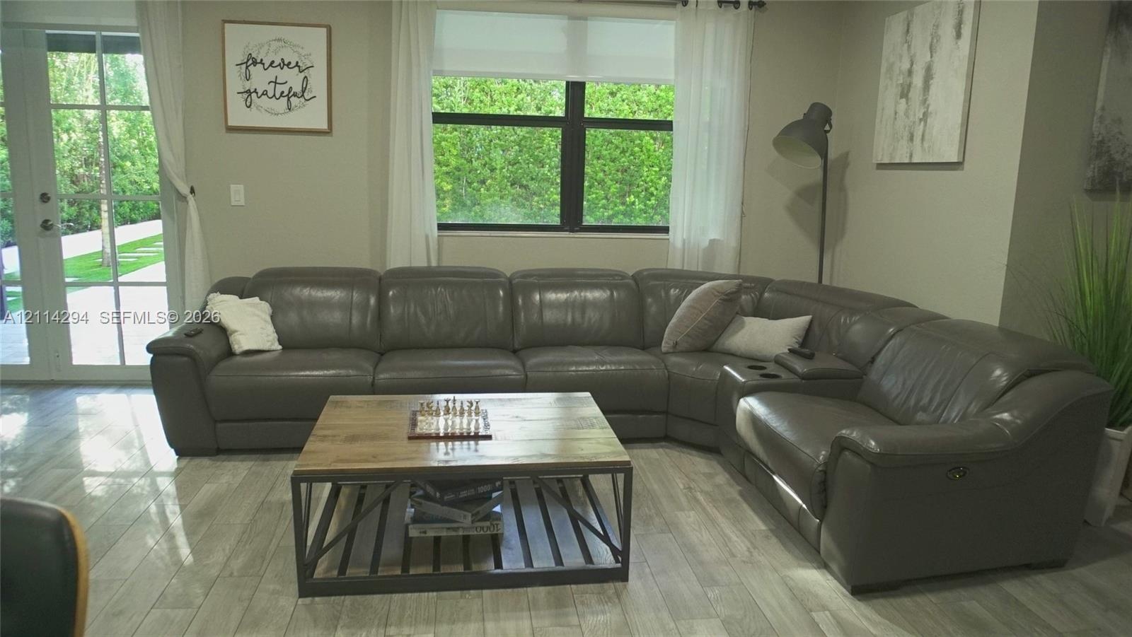 Neutral-toned living space featuring large-format ceramic tile flooring, a multi-pane glass door, and expansive windows