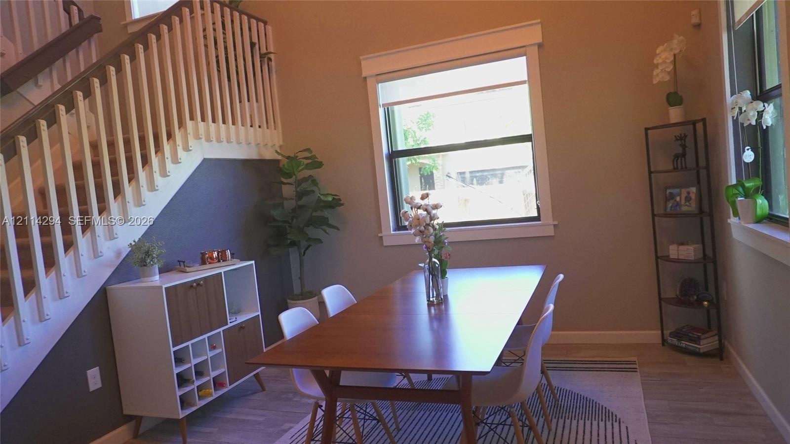 High-ceiling interior featuring a staircase with white balusters and wood-finish handrail, neutral wall tones, window with thick casing, and wood-fini