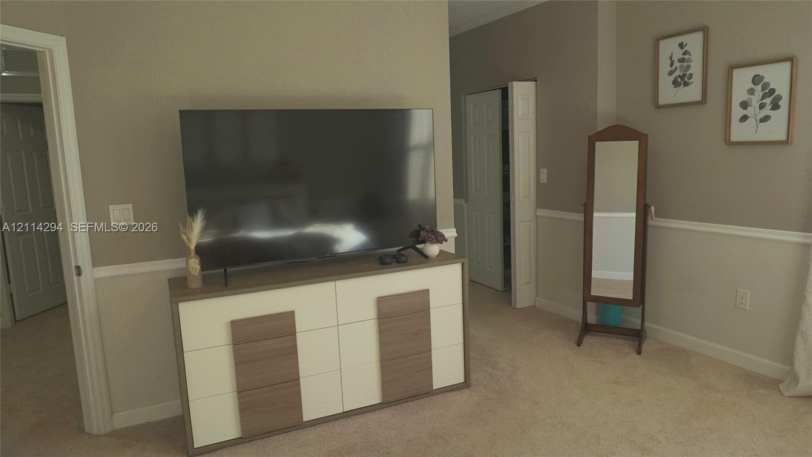 Interior space featuring neutral wall tones, white chair rail molding, carpeted flooring, and a multi-panel closet door