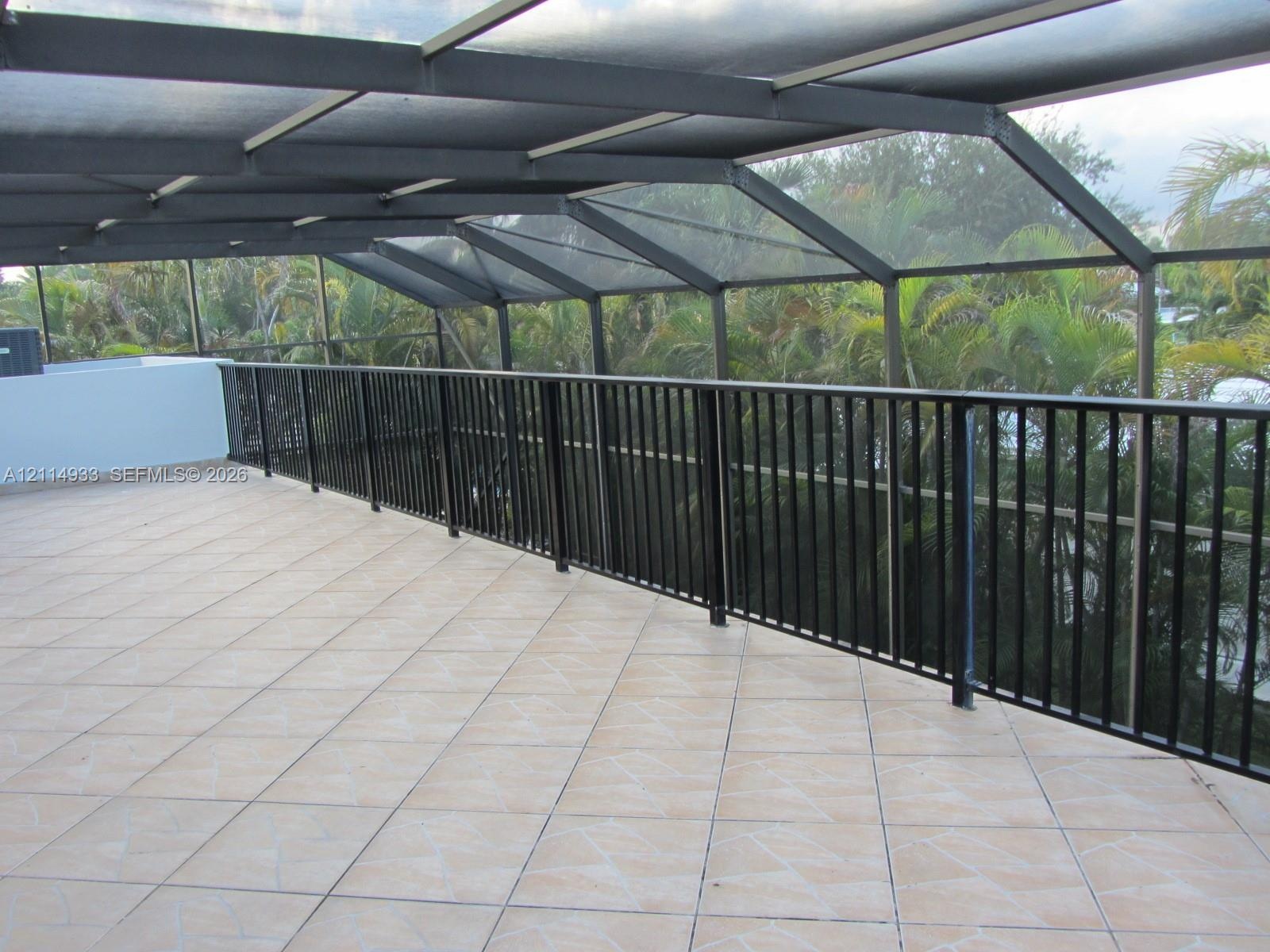 Screened-in balcony featuring tile flooring, metal structural framing, and a black vertical-slat railing