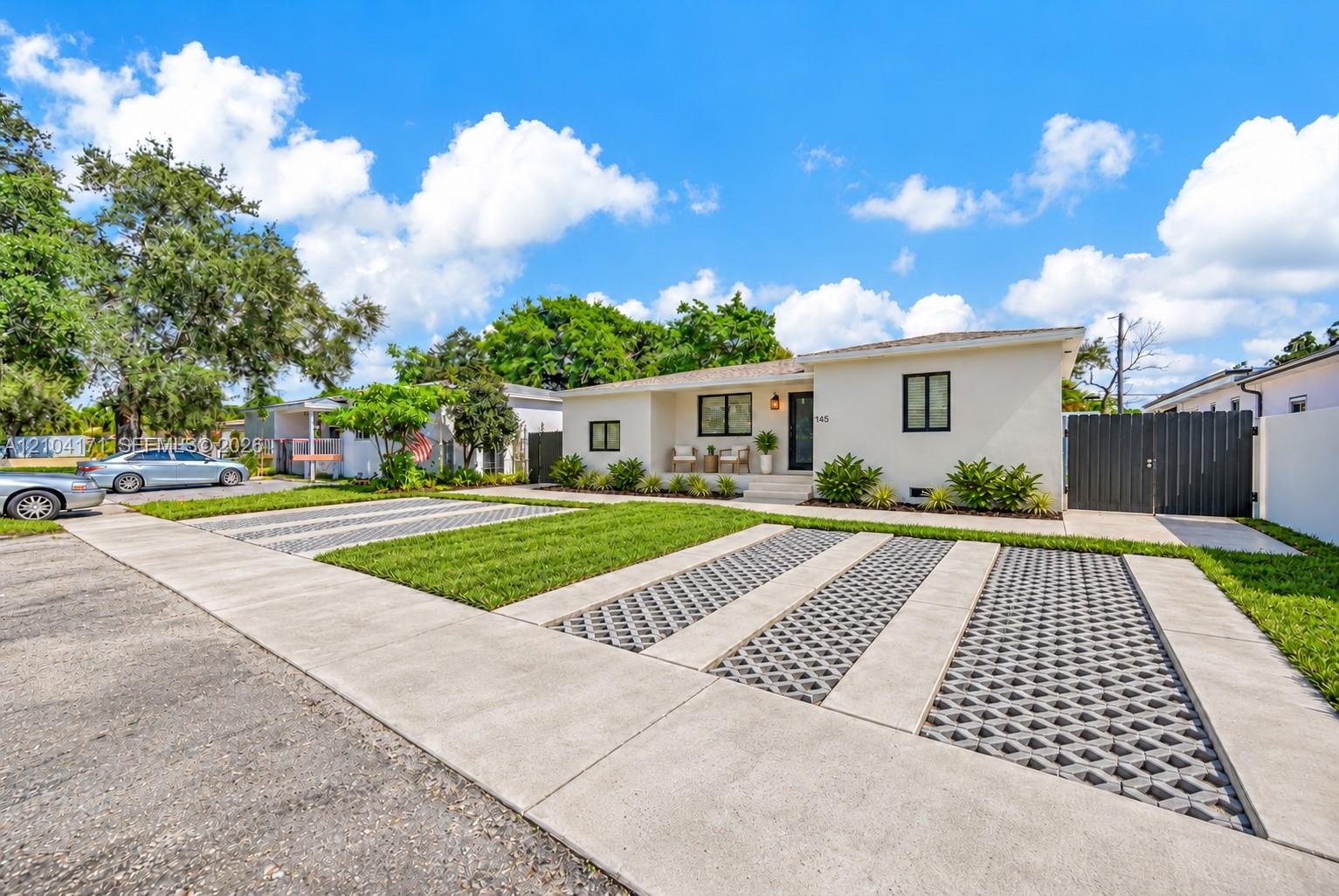 Expansive grass lawn featuring concrete patio landings, light-colored exterior finish, and mature palms
