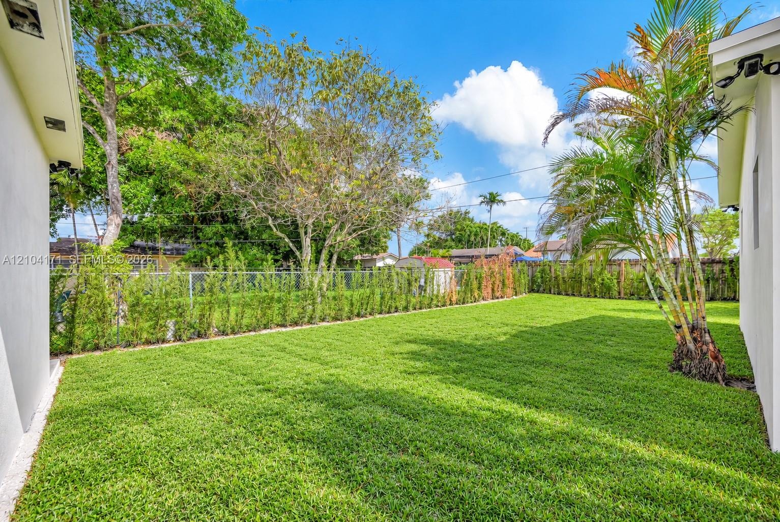 Single-story exterior featuring a light-toned stucco facade, multi-vehicle parking pad with decorative concrete pavers, and perimeter fencing