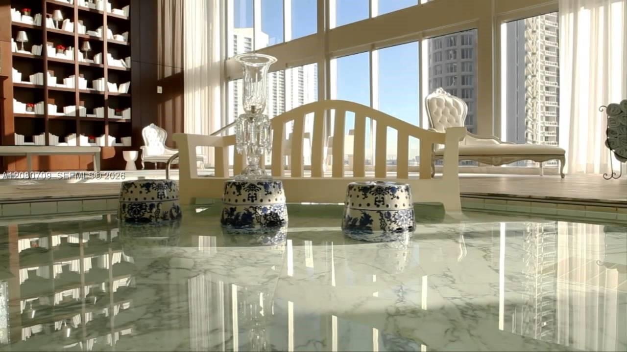 Floor-to-ceiling glass windows, wood-finish flooring, recessed lighting, and balcony access with water and city skyline surroundings