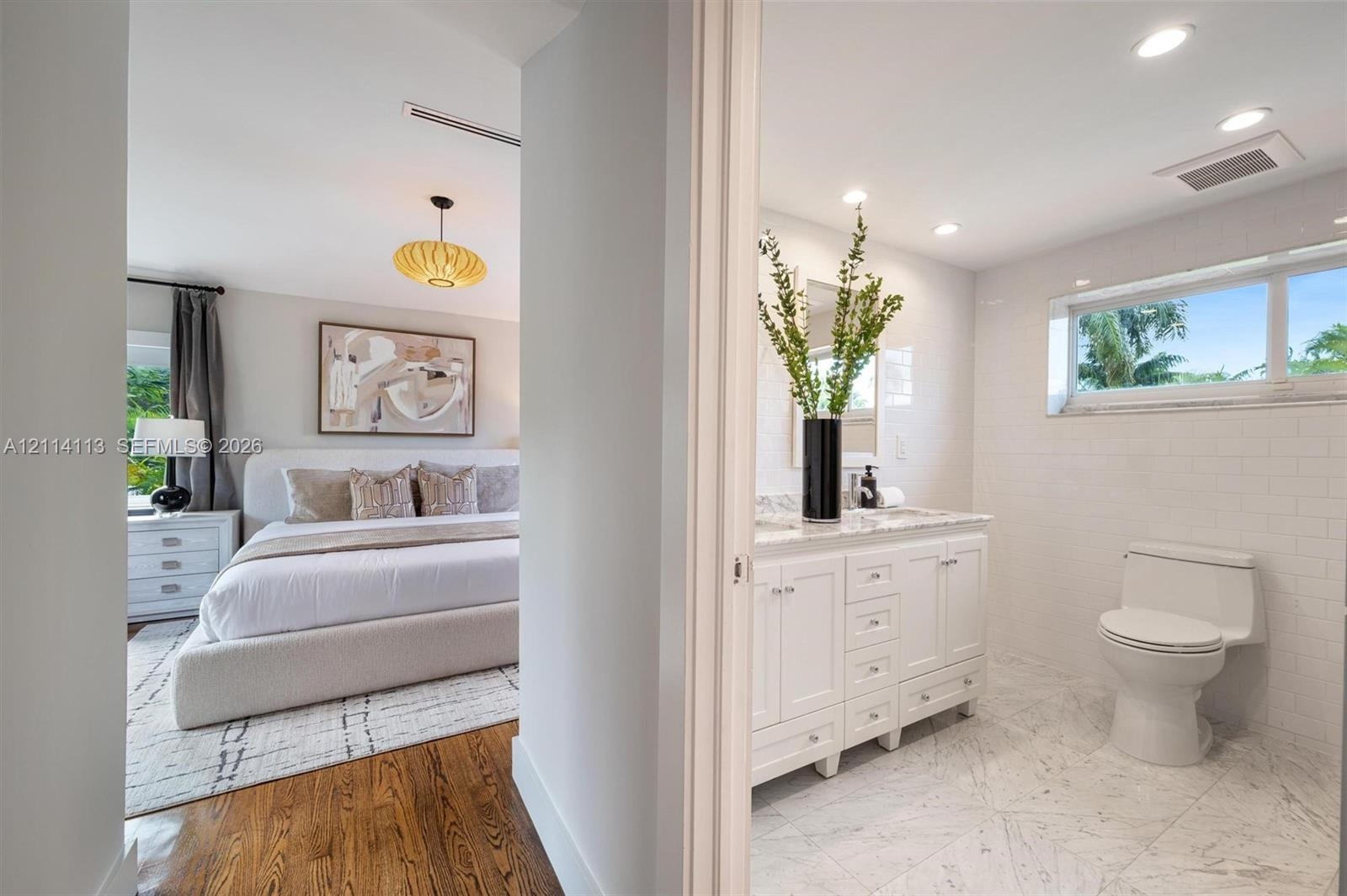 Bathroom featuring a white vanity with a marble countertop, white subway tile wall accents, and stone-finish floor tiling