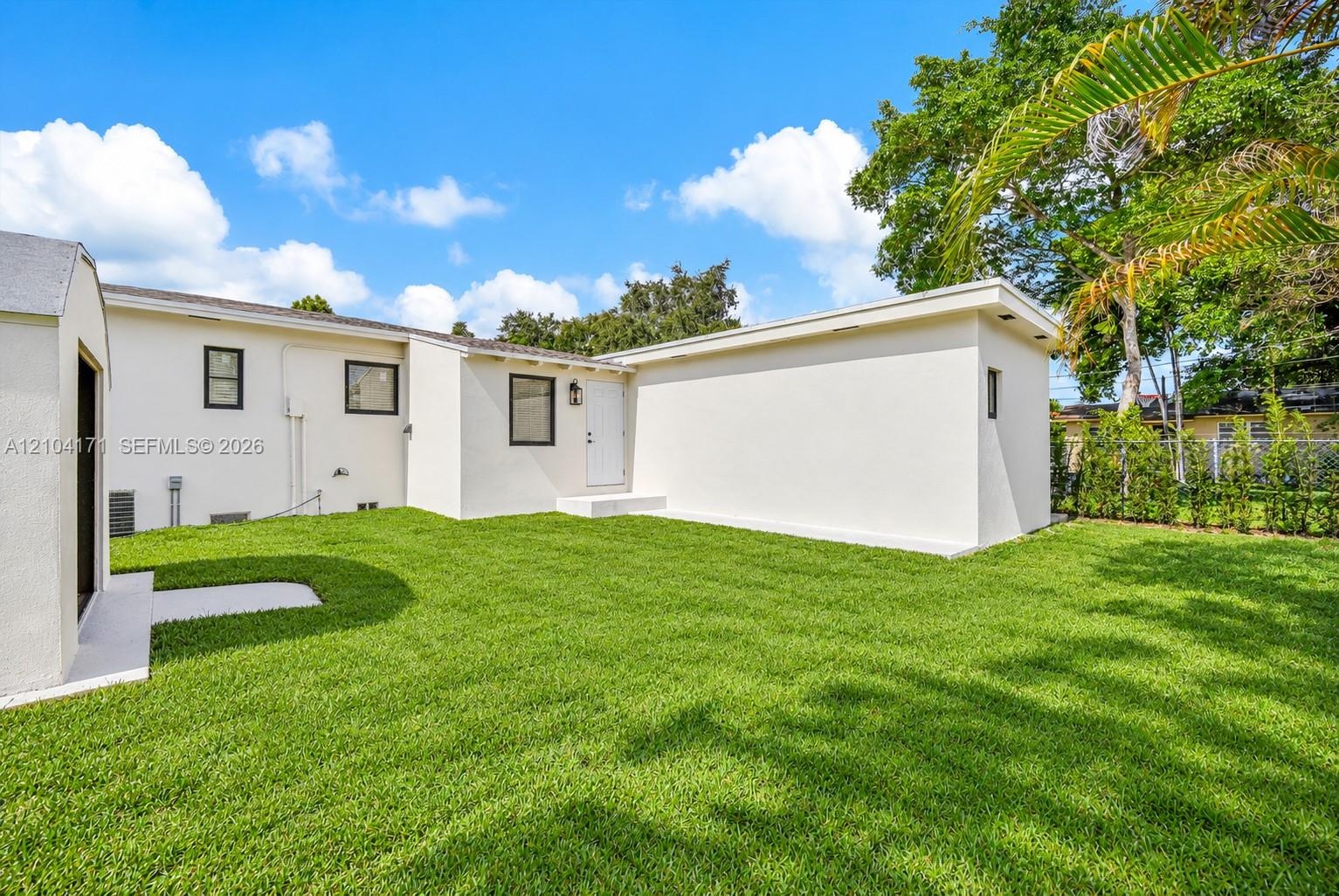 Backyard featuring a manicured lawn, perimeter masonry wall, detached storage structure, and exterior lighting fixtures