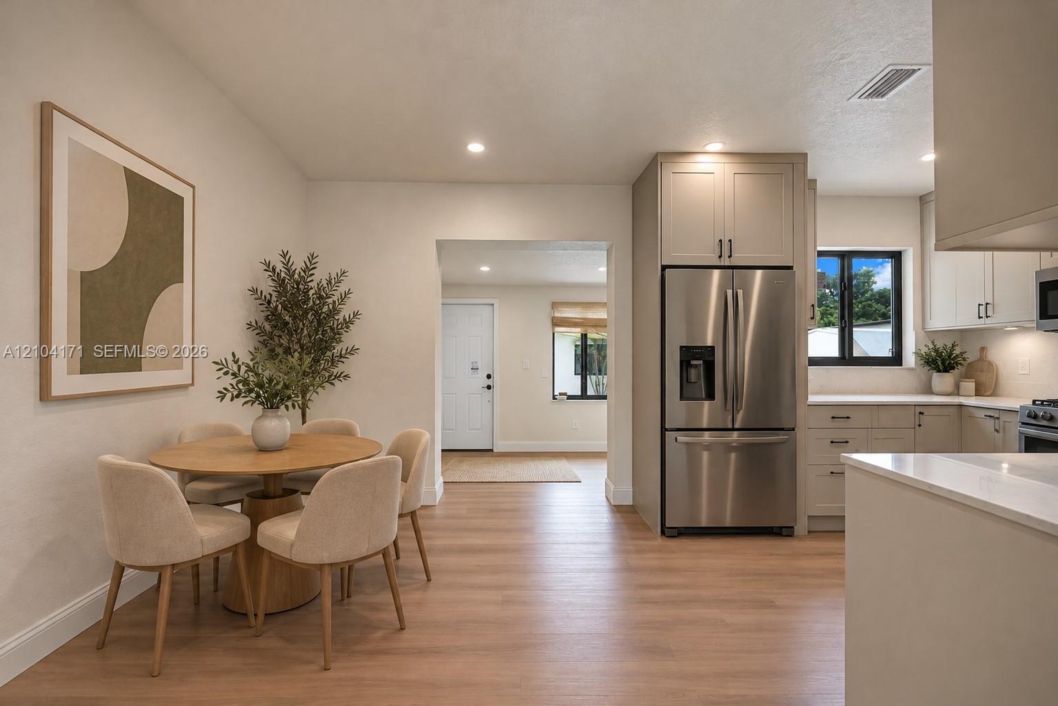 Kitchen featuring light-toned cabinetry, stainless steel refrigerator, stone countertops, and wood-finish flooring